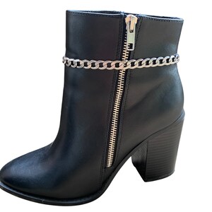 May include: Black ankle boots with a chunky heel and a silver chain detail around the ankle.
