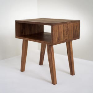 May include: A dark brown wooden end table with a shelf and four legs. The table has a simple, modern design.