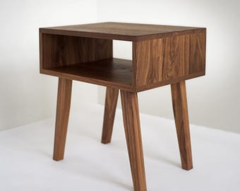 May include: A dark brown wooden end table with a shelf and four legs. The table has a simple, modern design.