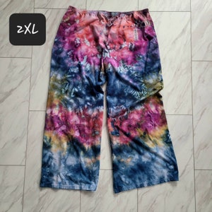 May include: Tie-dye wide-leg pants in shades of blue, pink, and yellow. The pants have a relaxed fit and a comfortable feel. The tag on the pants reads "2XL".