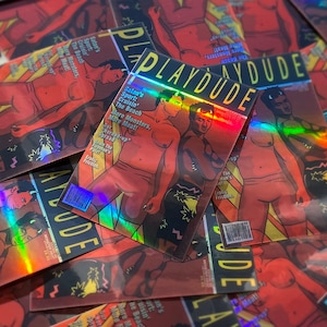 May include: A collection of rectangular holographic stickers featuring a magazine cover titled PLAYDUDE. The cover art depicts two figures with horns, wearing shorts, with text including Satan's Sport, Cruisin' The Beach, More Monsters, More Meat!