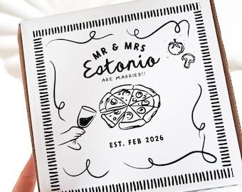 Może przedstawiać: Białe pudełko na pizzę z czarno-białymi ilustracjami pizzy, kieliszka wina i tekstem "MR & MRS Estonio ARE MARRIED!! EST. FEB 2026".