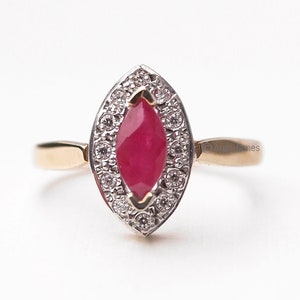 Op de afbeelding: Een gouden ring met een marquise-vormige robijn omringd door een halo van kleine diamanten.