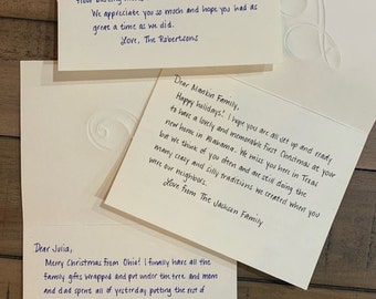 May include: Three handwritten greeting cards with blue ink on white paper are arranged on a wooden surface. The cards contain personal messages, with one addressed to "Aunt Jackie," another to "Mankin Family," and a third to "Julia."