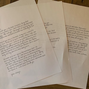 May include: Four sheets of white paper with handwritten text in black ink are arranged on a wooden surface. The text appears to be a love letter, with elegant cursive script. The papers are slightly crumpled, suggesting they have been handled.