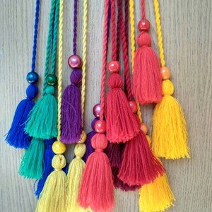 May include: A set of colorful tassel cords with wooden beads. The cords are in shades of blue, green, purple, red, and yellow.