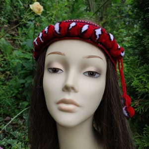 May include: A red and white headband with a crocheted design. The headband is worn on a mannequin with long brown hair.