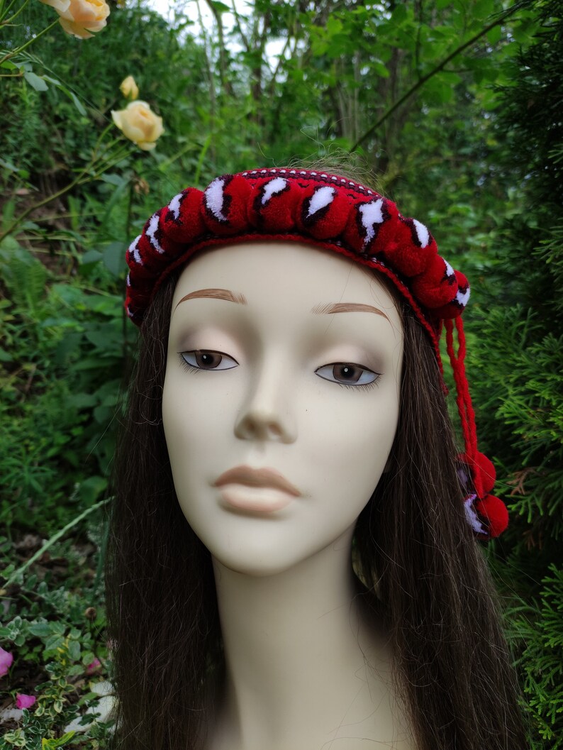 May include: A red and white headband with a crocheted design. The headband is worn on a mannequin with long brown hair.