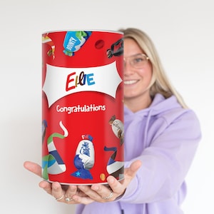 Könnte beinhalten: Ein roter zylinderförmiger Geschenkkarton mit dem Namen "Ellie" und dem Wort "Glückwunsch" aufgedruckt. Der Behälter ist mit Bildern verschiedener Süßigkeiten verziert.