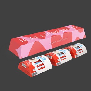 Peut inclure: Un coffret cadeau de Saint-Valentin. Une grande boîte rouge et rose avec le texte "ICH LIEBE DICH" et "SCHÖNEN VALENTINSTAG". En dessous, trois petites boîtes de barres chocolatées avec un emballage rouge et blanc. Le fond est gris foncé.