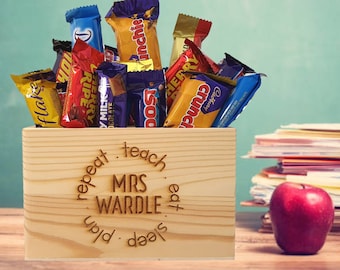 May include: A wooden box with the words "repeat teach MRS WARDLE sleep plan eat" engraved on the front. The box is filled with various chocolate bars, including Flake, Twirl, and Crunch.