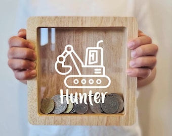 May include: Wooden piggy bank with a clear front panel, featuring a white outline of a digger and the name "Hunter". Coins are visible inside the bank.