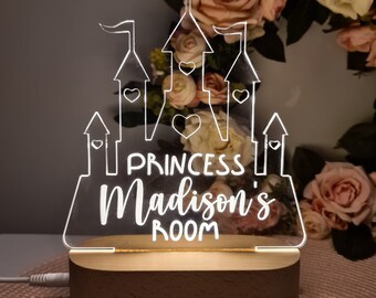 Puede incluir: Una luz nocturna de acrílico blanco con forma de castillo con las palabras "Princess Madison's Room" en ella. La luz nocturna está encendida y tiene una base de madera.
