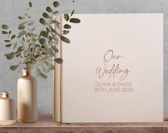 May include: A white wedding guest book with the text "Our Wedding" in a cursive font. The names Olivia & David and the date 30th June 2025 are printed below the title.