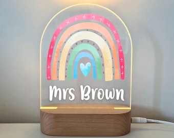May include: A rainbow-themed night light with a wooden base. The rainbow is made of pastel colors and has a heart in the center. The name "Mrs. Brown" is written below the rainbow.