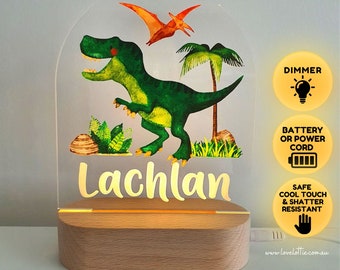 Puede incluir: Una luz nocturna personalizada de dinosaurio con un dinosaurio verde, un pterodáctilo rojo y naranja y palmeras. El nombre "Lachlan" está escrito en letras doradas en la parte inferior de la luz. La luz funciona con batería o con cable y tiene un atenuador.
