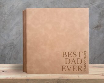 May include: A tan-colored, leather-bound book with the words "BEST DAD EVER" and "LOVE COOPER" printed on the front. The book is displayed on a wooden shelf against a gray background. Text Design 4 is at the bottom.