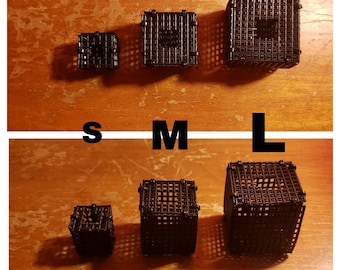 May include: Three black, square, mesh-style containers labeled S, M, and L. The containers are arranged in two rows, with the sizes increasing from left to right. The containers are made of a dark material and have a grid-like pattern.