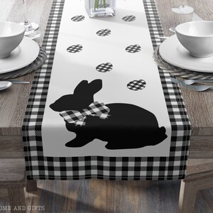 May include: Black and white checkered table runner with a black silhouette of a bunny wearing a bow tie and scattered black and white checkered eggs.