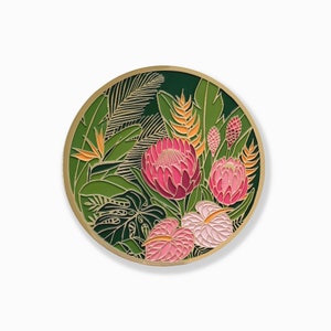 May include: A round, green enamel pin with a floral design. The pin features pink and orange flowers with green leaves.