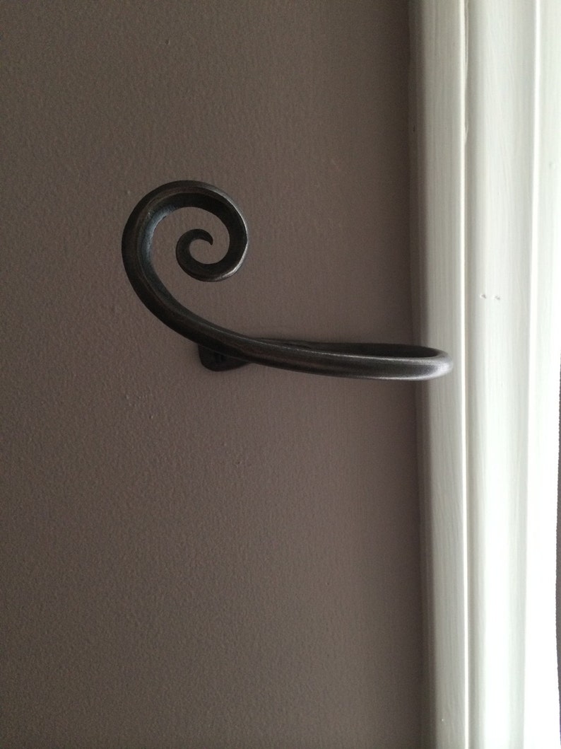 May include: A black metal towel rack with a decorative scroll design. The rack is mounted to a wall.