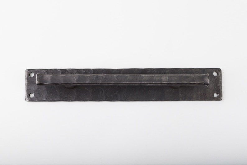 May include: A black metal door pull with a rectangular plate and a hammered finish.
