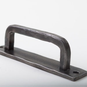 May include: A silver metal drawer pull with a rectangular base and a curved handle.