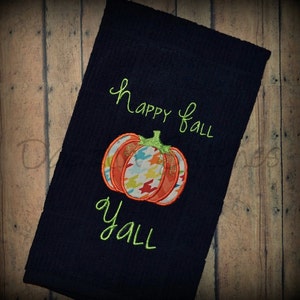 May include: A dark blue kitchen towel with the text "Happy Fall Y'all" embroidered in green. A colourful pumpkin with a green stem is embroidered in the centre of the towel.