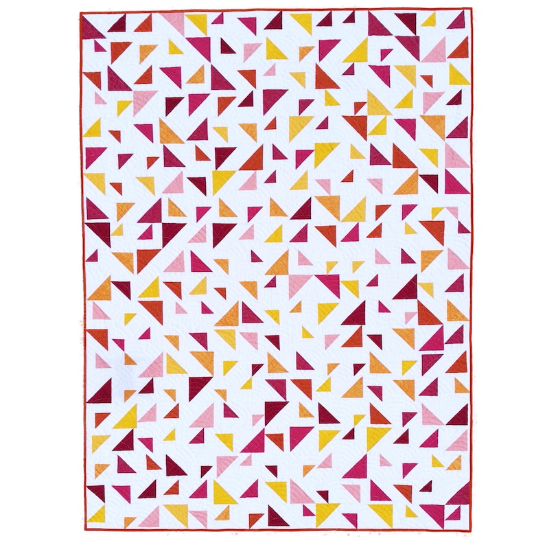 May include: A white quilt with a pattern of red, pink, and yellow triangles. The triangles are randomly arranged and create a modern and abstract design.