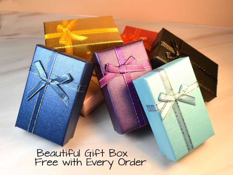 May include: A collection of colorful gift boxes, including blue, gold, purple, and black, each adorned with a matching ribbon. The boxes are arranged in a visually appealing display, with the text "Beautiful Gift Box Free with Every Order" at the bottom.