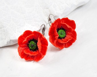 May include: A pair of red poppy flower earrings with green centers. The earrings are made of polymer clay and have silver hooks.