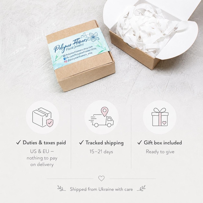 May include: A square brown cardboard gift box with a light blue floral label reading Polymer Flowers floral jewelry, accompanied by an open matching box filled with white crinkle paper filler, presented for jewelry packaging and presentation.