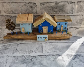 Lilly lane.3 cottages set on a driftwood lane with flowers a tree and blue fence with hand stamped plaque.