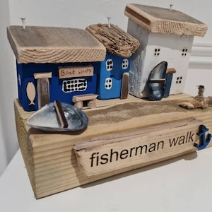 Fisherman walk. Row off cottages and bait shop,fishing boats,shingle,rocks and lasered signs. Driftwood and reclaimed wood.fathers day gift