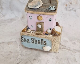 Sea shell's cottage.pretty coastal cottage next to the beach with rocks and shells. pastel colours.
