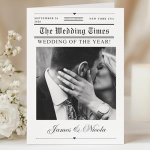 Puede incluir: Tarjeta de anuncio de boda en blanco y negro titulada "The Wedding Times". La tarjeta presenta una foto de una pareja besándose, con los nombres "James & Nicola" debajo. La fecha "26 de septiembre de 2026" está impresa en la parte superior.