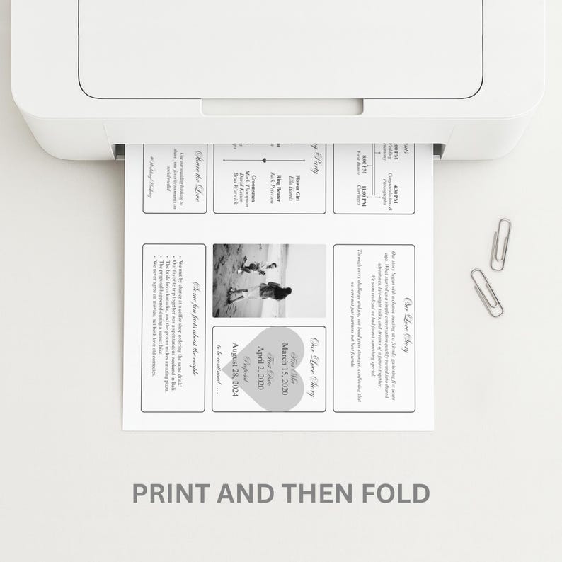 May include: A printed wedding invitation emerges from a white printer. The invitation features text and a black and white photo. The text includes wedding details and the phrase "Our Love Story". Two silver paper clips are on the white surface.
