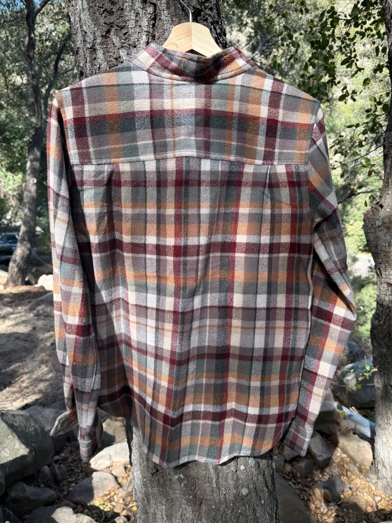 Pode incluir: Uma camisa de manga comprida xadrez com um padr&atilde;o xadrez marrom, bege, verde e vermelho. A camisa tem um colarinho abotoado e um caimento relaxado.