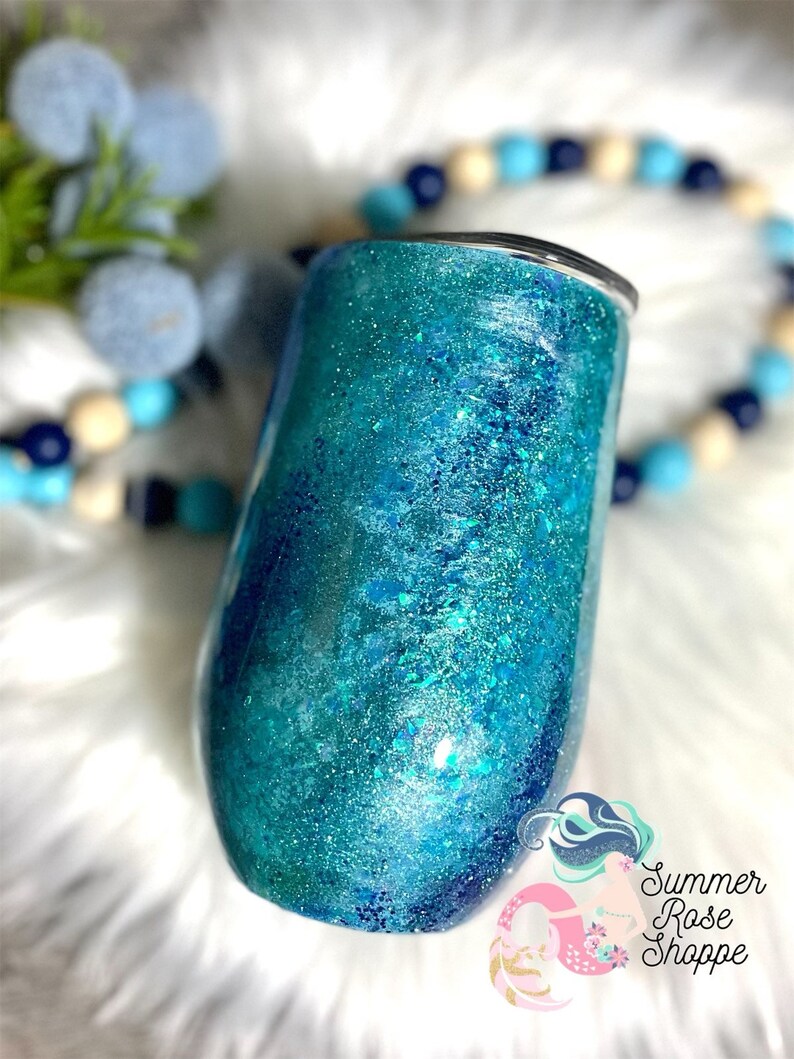 May include: A teal and blue glitter tumbler with a black lid. The tumbler has a shiny, textured surface with a gradient effect. The Summer Rose Shoppe logo is visible in the bottom right corner.