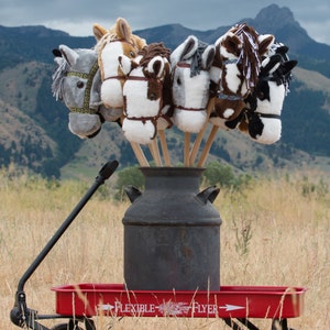 May include: A red wagon with a black milk can and six plush horse head toys on wooden sticks. The wagon has the words "Flexible Flyer" printed on the side.