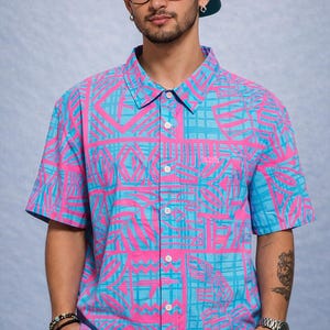 Op de afbeelding: Korte mouwen overhemd met een levendig roze en blauw geometrisch patroon. Het overhemd heeft een klassieke kraag en een borstzak. Het overhemd maakt deel uit van een casual kledingcollectie.