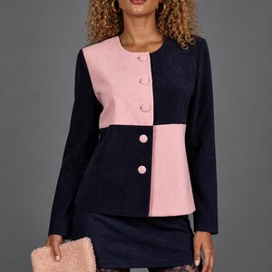May include: A two-tone, navy blue and pink jacket with matching buttons and a coordinating mini skirt. The outfit is paired with a small, fuzzy pink clutch. The model is wearing lace patterned tights.