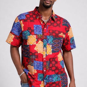 May include: Short-sleeved button-down shirt in a vibrant patchwork design. The shirt features a red base with colorful geometric patterns in blue, yellow, green, and black. The shirt has a classic collar and a chest pocket.