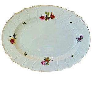 May include: A white oval serving platter with a scalloped edge and gold trim. The platter is decorated with hand-painted floral designs in shades of pink, yellow, orange, and purple.