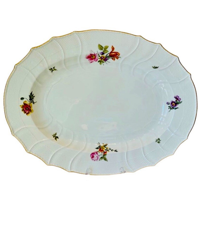 May include: A white oval serving platter with a scalloped edge and gold trim. The platter is decorated with hand-painted floral designs in shades of pink, yellow, orange, and purple.