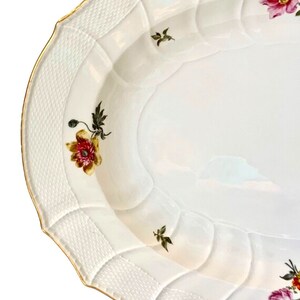 May include: White oval serving platter with a raised, woven pattern around the edge. The platter is decorated with hand-painted floral designs in shades of pink, red, yellow, and green.