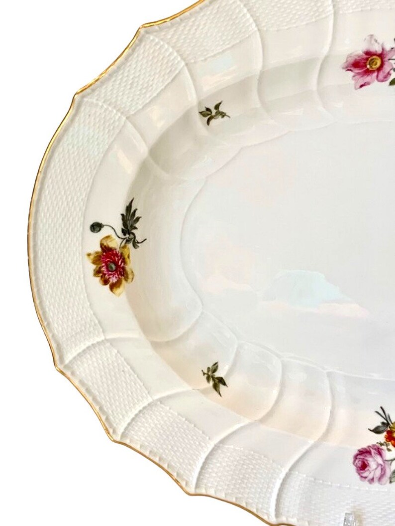 May include: White oval serving platter with a raised, woven pattern around the edge. The platter is decorated with hand-painted floral designs in shades of pink, red, yellow, and green.