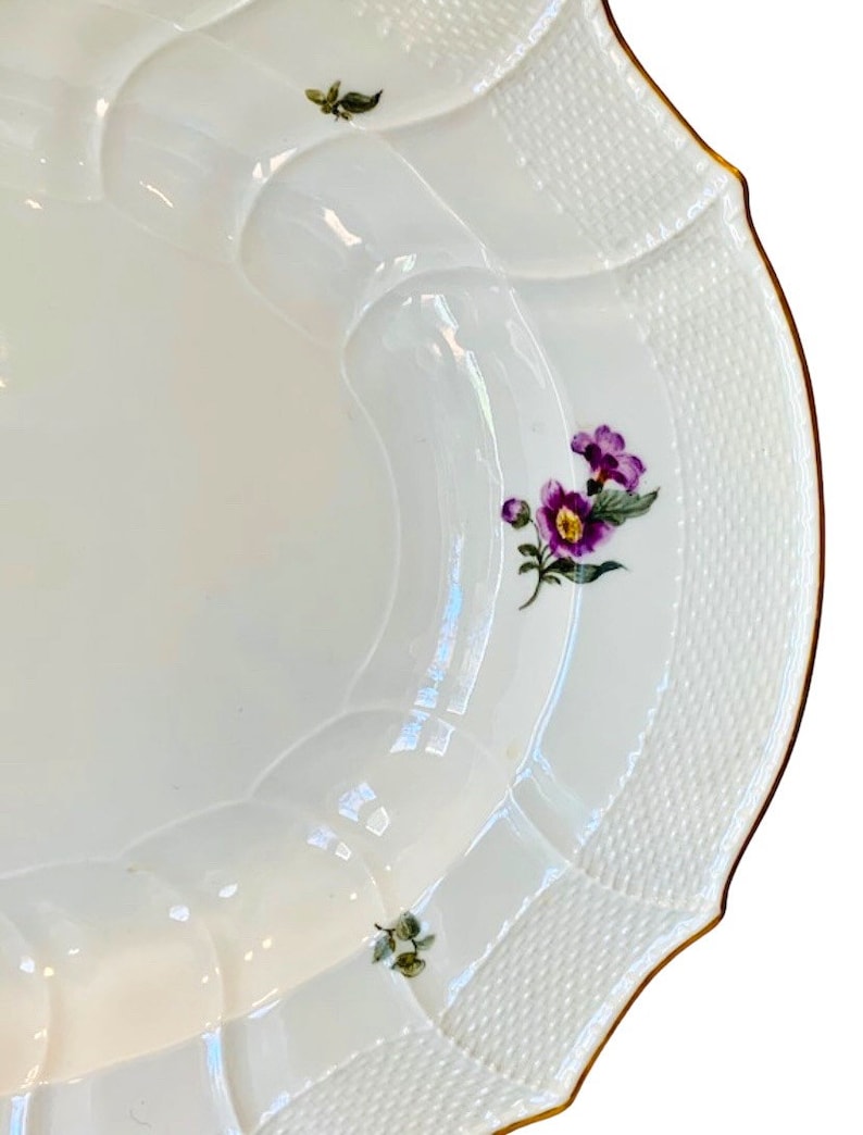 May include: White porcelain serving platter with a scalloped edge and a gold rim. The platter features a delicate floral design with purple flowers and green leaves.