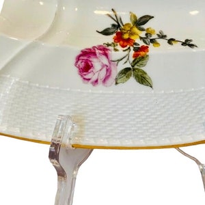 May include: White porcelain serving dish with a floral design featuring pink, red, yellow, and green flowers. The dish has a woven pattern around the edge and a gold trim.