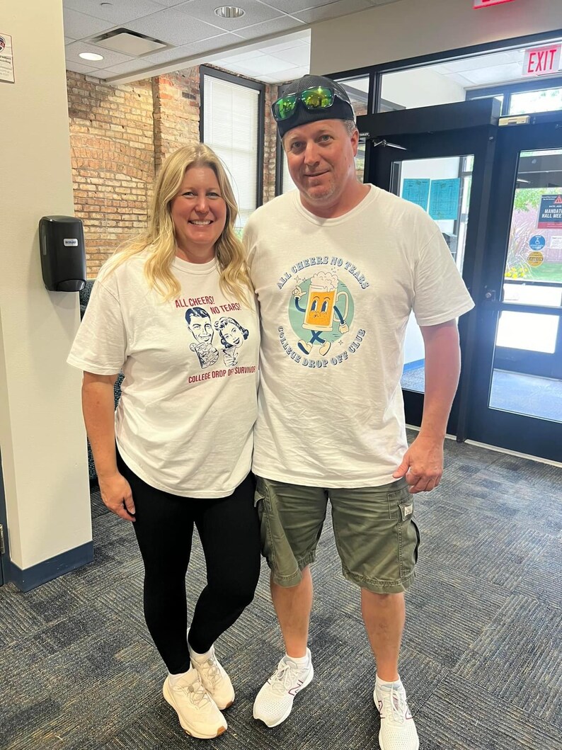 May include: Two people wearing white t-shirts with the text "All Cheers! No Tears! College Drop Off Club" and a cartoon beer mug. The man is wearing a black baseball cap and green cargo shorts. The woman is wearing black leggings.
